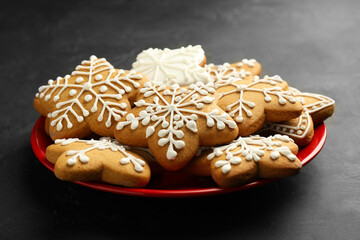 Tasty Christmas cookies with icing on black table, closeup