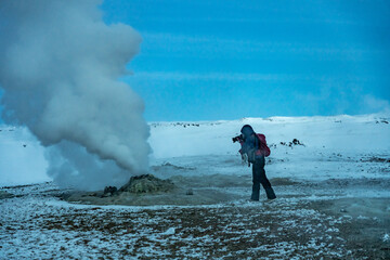 Adventurous photographer woman in winter in Iceland photographing in the Hverir or Namafjall Geothermal Area - obrazy, fototapety, plakaty