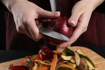 Woman peeling fresh onion with knife at table, closeup