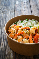 Takeaway food - fried shrimps with boiled white rice and lime in lunch box to go on wooden table  - 754875837