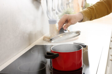 Woman cooking dinner on cooktop in kitchen, closeup