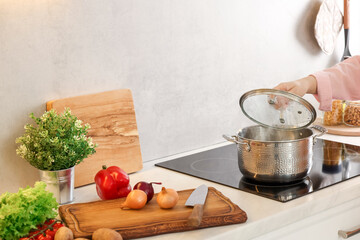 Woman cooking dinner on cooktop in kitchen, closeup