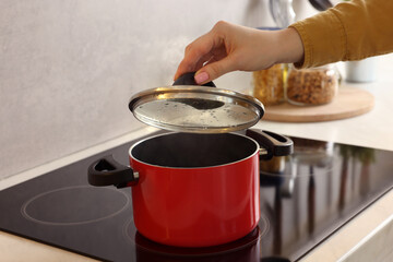 Woman cooking dinner on cooktop in kitchen, closeup