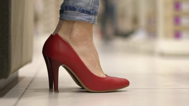 Trying on red high heels. Close-up of a woman's feet putting on shoes. A woman tries on shoes.