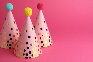 Beautiful party hats with pompoms on pink background, space for text