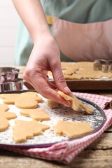 Woman making Christmas cookies at wooden table, closeup