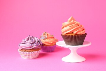 Delicious cupcakes with bright cream and sprinkles on pink background. Space for text