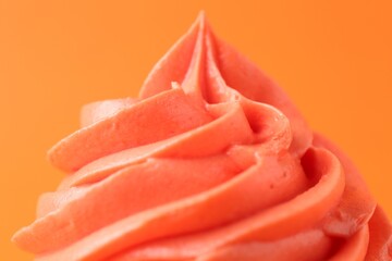 Delicious cupcake with bright cream on orange background, closeup