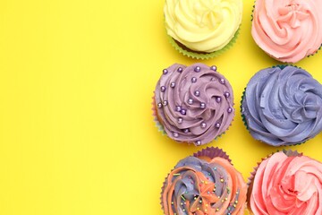 Delicious cupcake with bright cream on yellow background, flat lay. Space for text