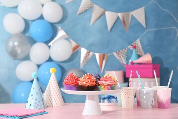 Different colorful cupcakes and party accessories on pink table