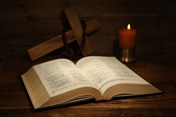 Obraz premium Bible, cross, rosary beads and church candle on wooden table