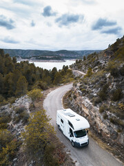 Motorhome on the road exploring in the nature surrounded by trees and next to a lake