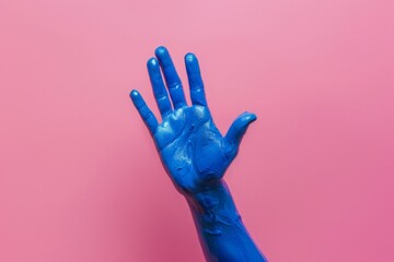 Obraz premium A persons hand with vibrant blue paint on it, creating a striking visual contrast. Isolated on pink background