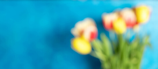 Defocused image with colorful tulips bouquet on bright blue background. Copy space.