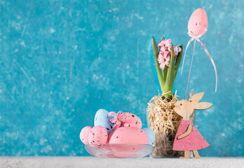 Vivid holiday card with pink Easter decorations on white table with turquoise backdrop. Copy space.