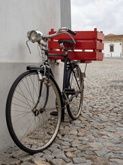 A vintage bike with a red wooden crate on the cargo rack. In the historic center of Évora, Portugal.