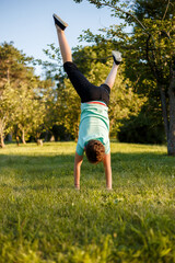 The boy with his head down, having fun in the park, doing acrobatics