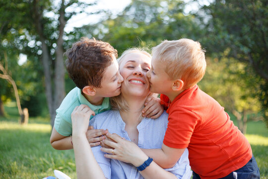 Mother with her kids they are together at a picnic, they hug each other. Outside portrait.