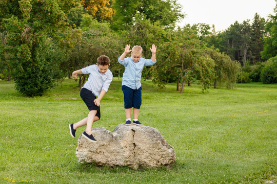 Full length image of the happy brothers jumping in the park. Space for text.