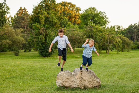 Full length image of the happy brothers jumping in the park.