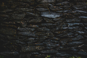 Black stone wall texture background. Close up of natural stone wall.