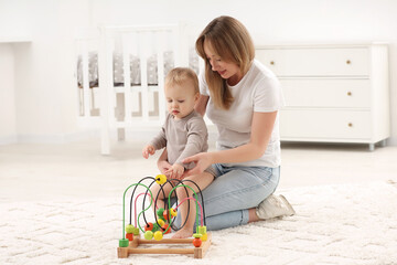 Children toys. Mother and her little son playing with bead maze on rug at home