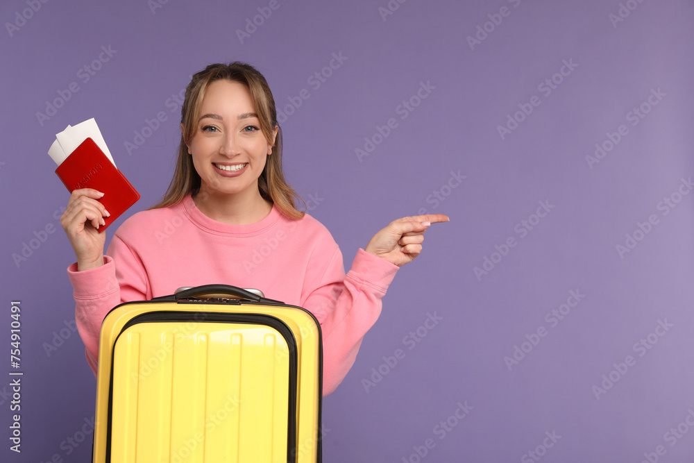 Sticker happy young woman with passport, ticket and suitcase pointing at something on purple background, spa