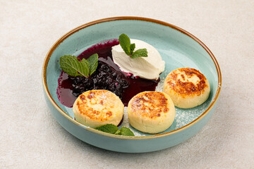 Portion of russian cottage cheese pancakes syrniki with berries and cream