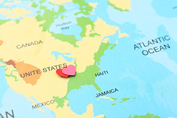 Fototapeta premium Honeymoon concept. Two red paper hearts on world map, closeup