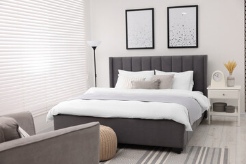Stylish bedroom interior with large bed, bedside table and lamp