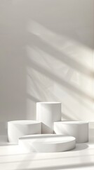 Fototapeta premium White cylindrical podiums in a minimalist setting with elegant shadow play, ideal for product display and contemporary design.