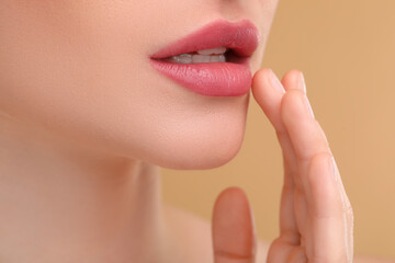 Young woman with beautiful full lips on beige background, closeup