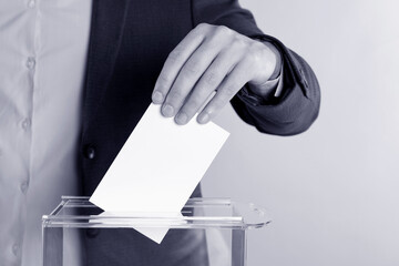 Man putting his vote into ballot box on background, closeup. Color toned