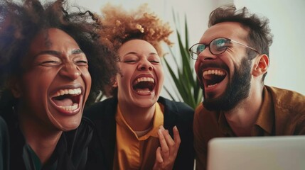 Happy businesspeople laughing while collaborating on a new project in an office. Group of diverse businesspeople using a laptop while working together in a modern workspace.