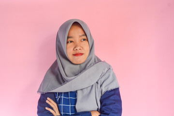 Young Asian woman standing very confidently facing the camera. Indonesian woman in blue shirt with gray hijab