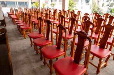 View of wooden chairs and red cushions arranged in rows on the concrete floor.