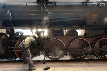 Fototapeta premium Maintenance work on vintage steam locomotive, Siena, Italy