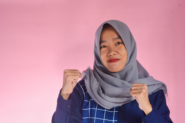 Young Asian woman standing very confidently facing the camera. Indonesian woman in blue shirt with gray hijab