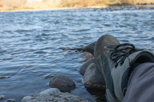 Pie con bota de hombre para cruzar encima de las piedras el río.