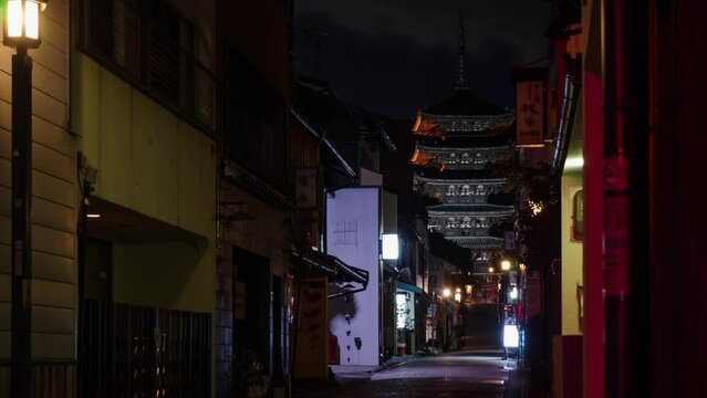 night time lapse view of local street with some traffic and people leads to ancient Yasaka pagoda building at higashiyama in Kyoto old town city
