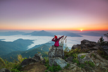 Young woman  in red jacket hiking on the high mountain, Doi Pha Tang, Chiang Rai province, border  of  Thailand and Laos. - obrazy, fototapety, plakaty