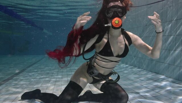 beautiful athletic girl model is engaged in diving in the pool in black stockings and a swimsuit, dancing underwater in the pool, underwater video