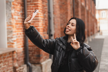 Happy young woman photographing herself using her mobile phone. Caucasian female taking selfie with...