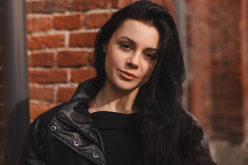 Beautiful woman smiling near brick wall. Outdoor portrait of a smiling brunette girl. Happy...