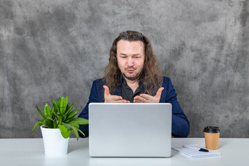 Young man with long hair deeply engrossed in working on his laptop in a contemporary office