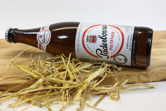 Eine Flasche Paderborner Pilsener, liegend auf einem geflammten Holzbrett, mit etwas Stroh zur Deko. 10.03.2024