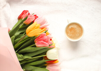 Beautiful tulips and cup of coffee on light, top view
