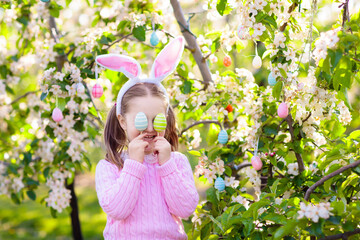 Child with bunny ears on garden Easter egg hunt - obrazy, fototapety, plakaty