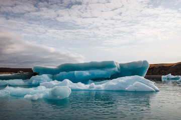 Icelandic glacial scenery, magnificent ice form, iceberg floating in the calm blue water, aerial...