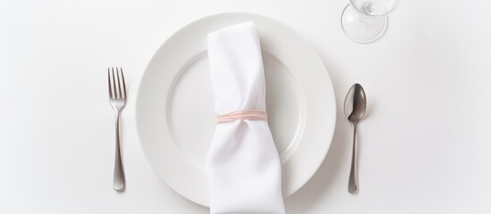 Tableware set on a plate includes fork, spoon, and glass with a napkin neatly folded on a table